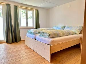 a bed with a wooden frame in a room with windows at Gasthof Ochsen in Nesslau