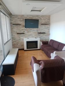 uma sala de estar com 2 sofás e uma televisão de ecrã plano em Departamento completo 2 em Quito