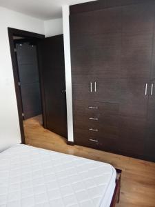 um quarto com armários castanhos e um colchão branco em Departamento completo 2 em Quito