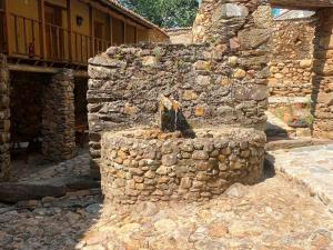 a stone wall with an outdoor fireplace in front of a building at Quinta da Maria Mendes in Serpins