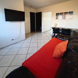 sala de estar con sofá rojo y TV de pantalla plana en Casa privativa próximo ao centro e aeroporto. en Campo Grande