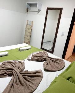 a bed with towels on it with a mirror at Casa privativa próximo ao centro e aeroporto. in Campo Grande