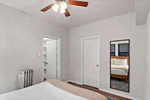 a white bedroom with a ceiling fan and a mirror at Modern Chic 1BR in Downtown Chicago - Dorchester 204 in Chicago