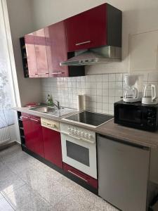 a kitchen with red cabinets and a stove and a sink at Stilvolles Zuhause in Magdeburg