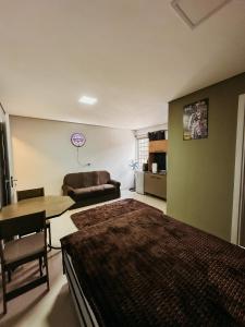 een slaapkamer met een bed, een tafel en een bank bij Apartamento ótima localização in Passo Fundo
