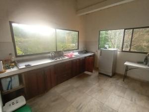 a kitchen with a sink and a refrigerator and two windows at Hotel San Cayetano in Arimaca
