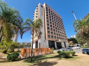 a large building with palm trees in front of it at Flat 609 - Comfort Hotel Taguatinga in Brasília