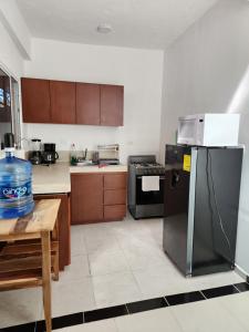 Il comprend une cuisine équipée d'un réfrigérateur et d'une table avec une bouteille d'eau. dans l'établissement Casa de 3 recamaras frente al parque, à Mérida