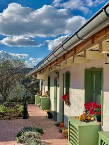 un edificio con puertas verdes y flores. en Pannonhalma Várlak Vendégház, en Pannonhalma