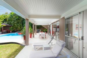 un patio al aire libre con piscina y silla en Villa Lodge - Bas de Villa avec piscine et vue océan et Moorea en Punaauia