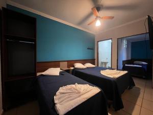 a room with two beds and a ceiling fan at Hotel Cesar Nogueira in Aparecida