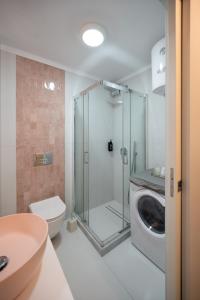 a bathroom with a shower and a toilet and a washing machine at La Luna Lux Studio in Ioannina