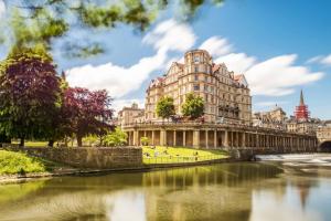 a building next to a river in front of a building at Pass the Keys 2 bed flat in fabulous location with parking in Bath