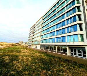 un edificio en la playa con un campo de césped al lado en Skyline suite 2, en Oostduinkerke