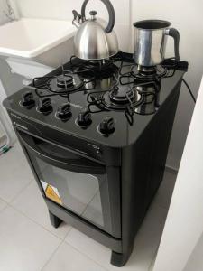 a black stove with a tea kettle on top of it at Apartamento completo, privativo, ótima localização (Próximo ao Aeroporto) in Campo Grande