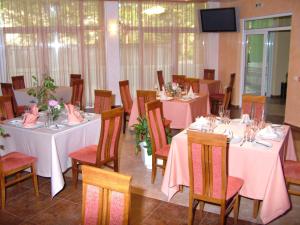 a dining room with tables and chairs with pink tablecloths at Family Hotel Gabrovo in Gabrovo