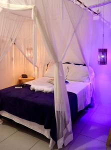 1 dormitorio con cama con dosel y luces moradas en Res. Orion Praia do Espelho en Praia do Espelho