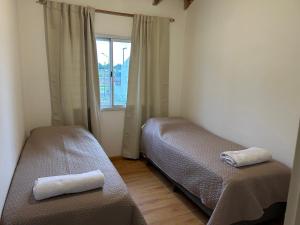 a small bedroom with two beds and a window at Duplex 2 Dormitorios Neuquén in Neuquén