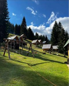 a field with a group of wooden buildings and trees at Eko Katun Bungalows Jelovica in Berane