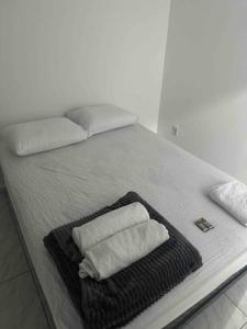 a bed with two towels and two pillows on it at Studio novo 2024 próx. Aeroporto in Passo Fundo