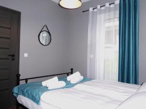 ウストロンにあるApartament Olchowe Zaciszeのベッドルーム1室(青いカーテンと鏡付きのベッド1台付)