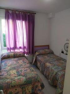 a bedroom with two beds and a window with purple curtains at casa santa susanna Paula Aroa in Santa Susanna