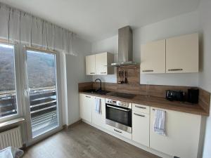 a kitchen with white cabinets and a large window at Pension mit Moselblick in Klotten