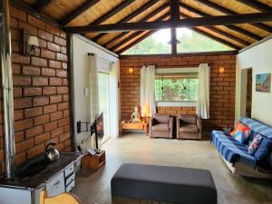 a living room with a blue couch and a brick wall at Refúgio Tao Cerrado Chalé Pé de Serra in Alto Paraíso de Goiás