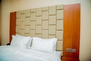 ANINY HOTEL في دار السلام: غرفة نوم بسرير كبير ومخدات بيضاء