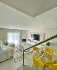 a white living room with yellow chairs and a couch at Home Silva Sanches in Quinta do Conde