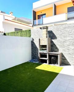 uma casa com um quintal com lareira e relva em Home Silva Sanches em Quinta do Conde