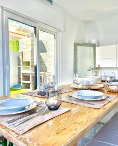 una mesa de madera con platos y copas de vino. en Home Silva Sanches en Quinta do Conde