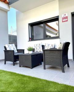 eine Terrasse mit Korbstühlen und einem Tisch in der Unterkunft Home Silva Sanches in Quinta do Conde