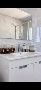 a white bathroom with a sink and a mirror at Home Silva Sanches in Quinta do Conde