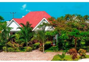 une grande maison blanche avec un toit rouge dans l'établissement Taj hotel partnership, à Nungwi