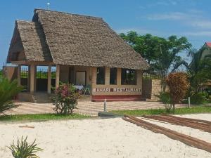 - un petit bâtiment avec un toit de paille sur la plage dans l'établissement Taj hotel partnership, à Nungwi
