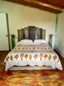a bedroom with a bed with a comforter on it at Cabaña en el bosque de Chiloé in Quemchi