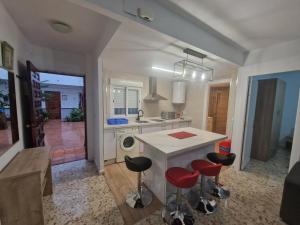 a kitchen with a white counter and red stools at Apartamentos en Patio Cordobés San Basilio in Córdoba