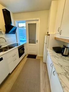 cocina con armarios blancos y puerta con ventana en Cozy Home in Downtown Reykjavik, en Reikiavik