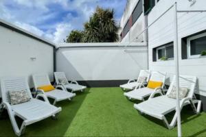 a group of white chairs sitting on a lawn at Urban Park House in Fajã de Baixo