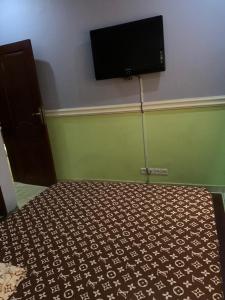 a bedroom with a bed with a flat screen tv on the wall at Résidence Longchamp in Douala