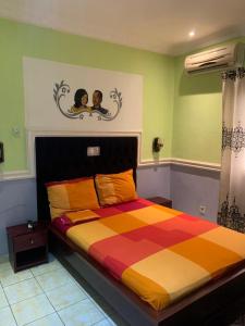 1 dormitorio con 1 cama grande y edredón colorido en Résidence Longchamp, en Douala