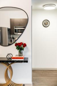 a mirror on a table with a vase of red flowers at Luxurious Hollywood condo in Los Angeles