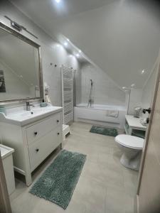 a white bathroom with a sink and a toilet at Galéria Apartmanház in Keszthely