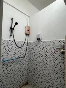 a shower in a bathroom with black and white tiles at Happiness Hostel in Phra Ae beach