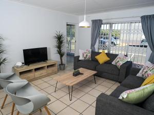 a living room with a couch and a tv at Big Bay Beach Club in Cape Town