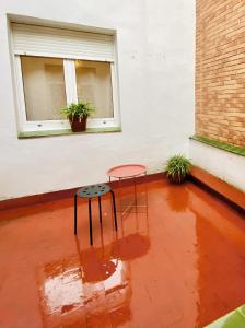 un suelo rojo con una mesa y un taburete frente a una ventana en Amplio apartamento con dos patios y aparcamiento privado en Gijón
