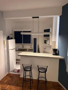 a kitchen with two bar stools and a counter top at Apartamento no coração de Belo Horizonte [2] in Belo Horizonte