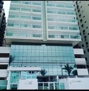 een hoog glazen gebouw met palmbomen ervoor bij AP do JP in Praia Grande