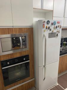 een witte koelkast in een keuken naast een magnetron bij AP do JP in Praia Grande